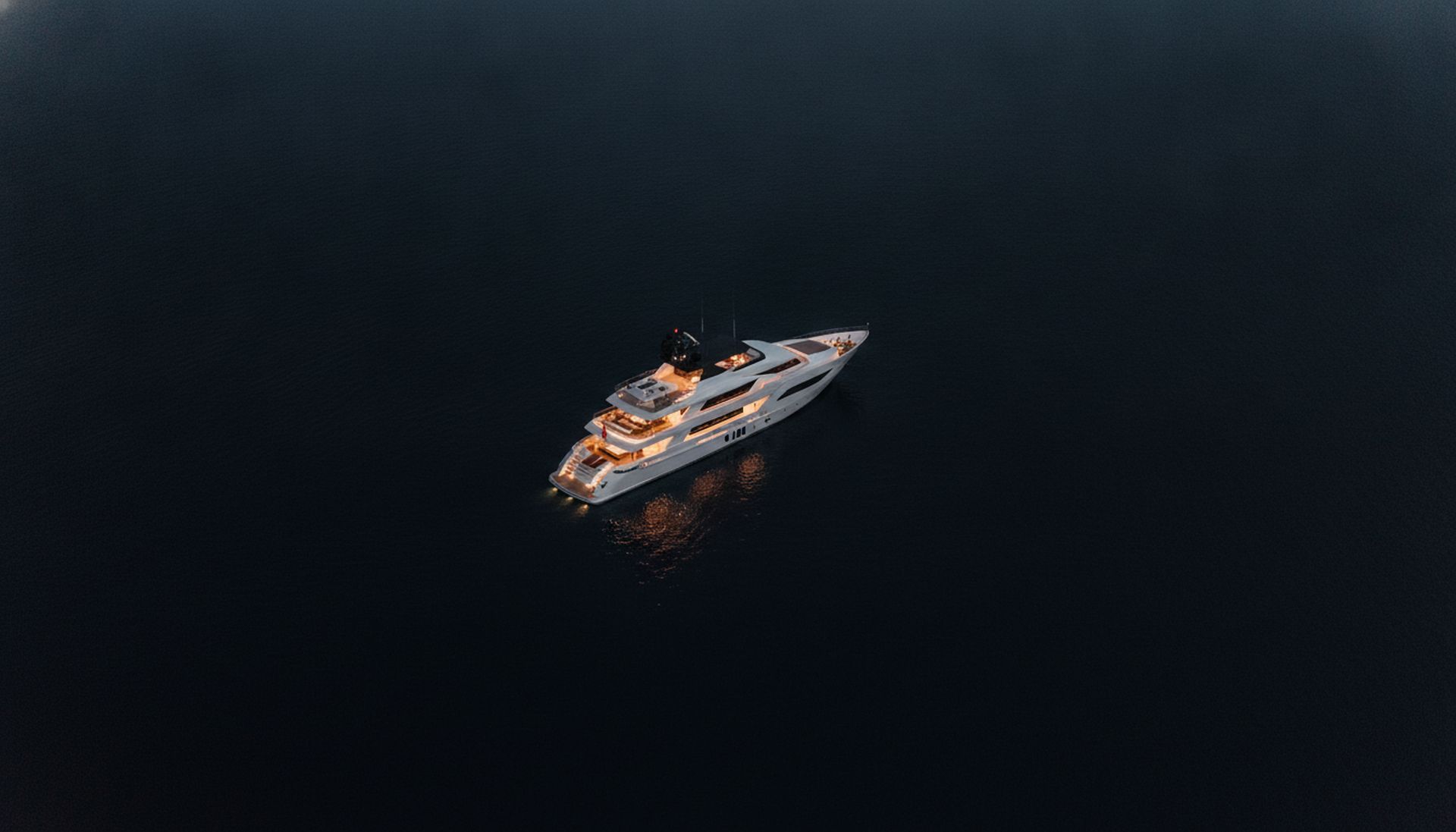 A motor superyacht at anchor at dusk, seen from above